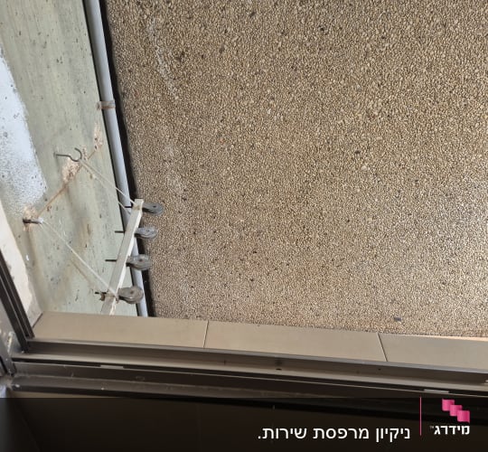 מתקן כביסה חיצוני עם גלגלות על קיר בטון